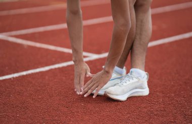 Athletes sport man runner wearing white sportswear to stretching and warm up before practicing on a running track at a stadium. Runner sport concept.