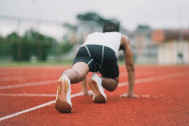 Athletes sport man runner wearing white sportswear to stretching and warm up before practicing on a running track at a stadium. Runner sport concept.