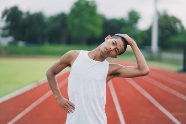 Athletes sport man runner wearing white sportswear to stretching and warm up before practicing on a running track at a stadium. Runner sport concept.