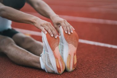 Athletes sport man runner wearing white sportswear to stretching and warm up before practicing on a running track at a stadium. Runner sport concept.