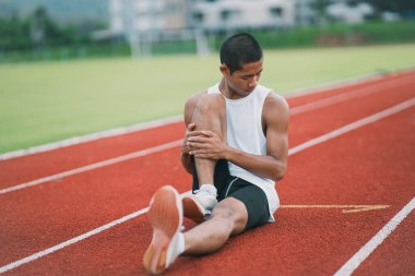 Athletes sport man runner wearing white sportswear to stretching and warm up before practicing on a running track at a stadium. Runner sport concept.