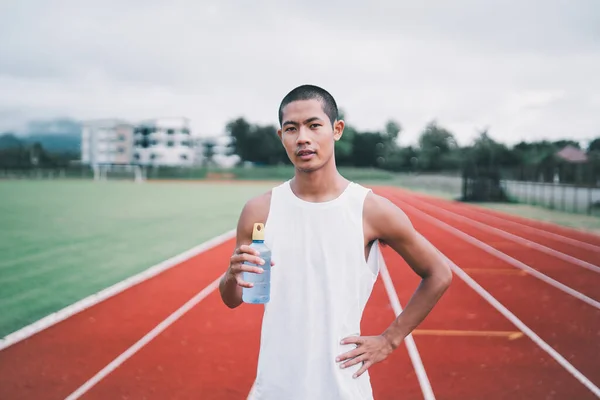 Attractive Asian sport man runner tired and thirsty after running workout drinking water. Sport man concept