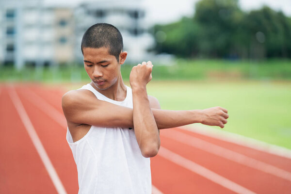 Athletes sport man runner wearing white sportswear to stretching and warm up before practicing on a running track at a stadium. Runner sport concept.