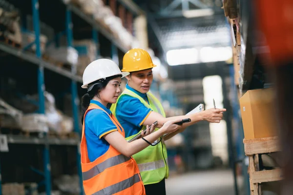 Young Asian woman worker using barcode scanner checking goods and box shelf stock in the warehouse factory store, co-worker man counting check stock. Warehouse Logistic concept.