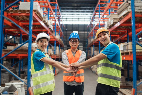 Group of industrial warehouse asian worker in safety suite hand stack celebrate successful or deal commitment. Logistics , supply chain and warehouse business.Teamwork unity under view concept.