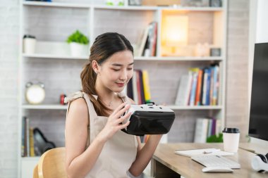 Asian woman smile and play VR game, 3D divice new innovation glasses for entertain at home, asian woman joyful in house on holiday. Happy woman playing metaverse VR technology concept.