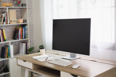 Close up view of worktable with laptop or computer, tablet, notebook and pen in home office room. Work at home place in the living room concept.