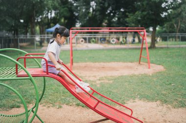 Okulda, anaokulunda ya da çocuk parkında oynayan tatlı Asyalı kız. Çocuklar için sağlıklı bir yaz aktivitesi. Küçük Asyalı kız çocuk parkında dışarı tırmanıyor. Çocuk dışarıda oyun oynuyor..