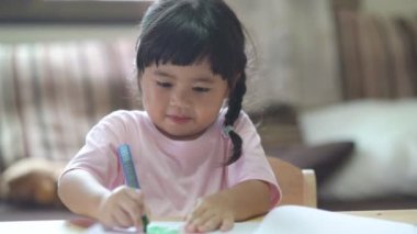 Cute little child painting with colorful paints. Asian girl and her mother using crayon drawing color. Baby artist activity lifestyle concept.
