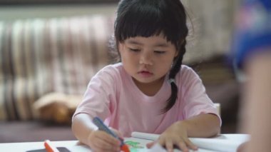 Cute little child painting with colorful paints. Asian girl and her mother using crayon drawing color. Baby artist activity lifestyle concept.