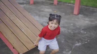 Okulda, anaokulunda ya da çocuk parkında oynayan tatlı Asyalı kız. Çocuklar için sağlıklı bir yaz aktivitesi. Küçük Asyalı kız çocuk parkında dışarı tırmanıyor. Çocuk dışarıda oyun oynuyor..