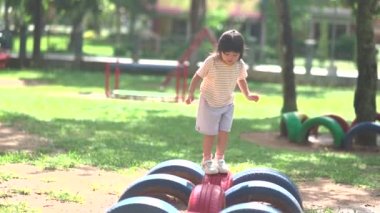 Cute asian girl smile play on school or kindergarten yard or playground. Healthy summer activity for children. Little asian girl climbing outdoors at playground. Child playing on outdoor playground.