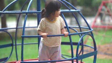 Cute asian girl smile play on school or kindergarten yard or playground. Healthy summer activity for children. Little asian girl climbing outdoors at playground. Child playing on outdoor playground.