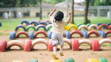 Cute asian girl smile and play on school or kindergarten yard or playground. Healthy summer activity for children. Little asian girl climbing outdoors at playground. Child playing on outdoor playground.