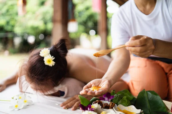 Hand of masseuse use honey for massage and spa relaxing treatment of office syndrome traditional thai massage style. Female masseuse doing massage scrup with salt treat back pain, arm pain and stress