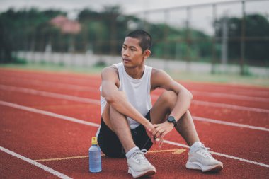 Athletes runner sport man resting bottle water tired and thirsty  practicing on a running track at a stadium. Running workout drinking water. Sport man run concept.