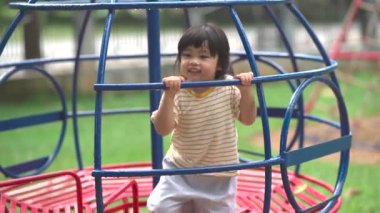 Cute asian girl smile play on school or kindergarten yard or playground. Healthy summer activity for children. Little asian girl climbing outdoors at playground. Child playing on outdoor playground.