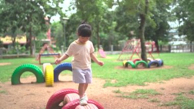 Cute asian girl smile play on school or kindergarten yard or playground. Healthy summer activity for children. Little asian girl climbing outdoors at playground. Child playing on outdoor playground.