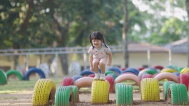 Cute asian girl smile play on school or kindergarten yard or playground. Healthy summer activity for children. Little asian girl climbing outdoors at playground. Child playing on outdoor playground.