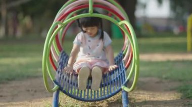 Cute asian girl smile play on school or kindergarten yard or playground. Healthy summer activity for children. Little asian girl climbing outdoors at playground. Child playing on outdoor playground.