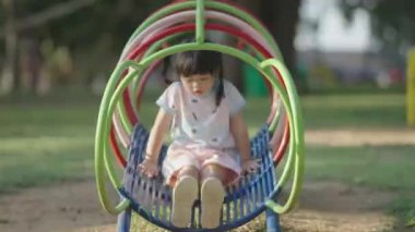 Cute asian girl smile play on school or kindergarten yard or playground. Healthy summer activity for children. Little asian girl climbing outdoors at playground. Child playing on outdoor playground.