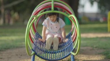 Cute asian girl smile play on school or kindergarten yard or playground. Healthy summer activity for children. Little asian girl climbing outdoors at playground. Child playing on outdoor playground.
