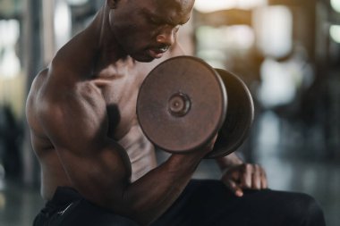 Afrikalı sporcu güçlü kas egzersizi spor salonundaki spor salonunda halterle ağırlık egzersizi yapıyor. Vücut geliştirme sporu konsepti.