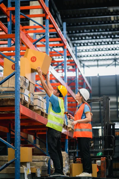 Asian warehouse workers lifting boxes on the shelf checking goods box shelf stock and standing on floklift in the warehouse factory store,worker barcode scaner check stock. Warehouse Logistic concept.