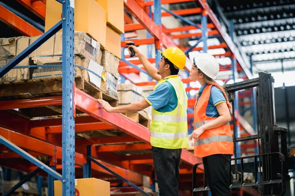 Asian warehouse workers using barcode scanner checking goods and box shelf stock and standing on floklift in the warehouse factory store,worker counting check stock. Warehouse Logistic concept.
