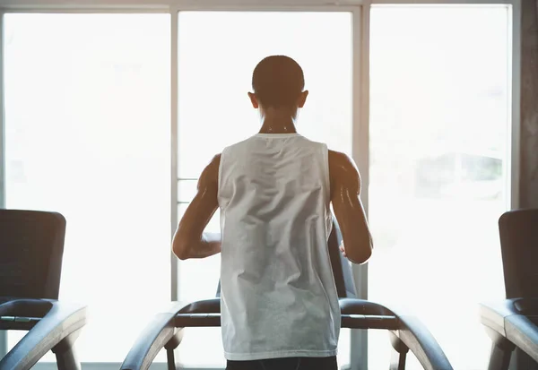 Back side of asian athlete sportsman runner tan skin running on treadmill in fitness club. Cardio workout. Healthy lifestyle, guy training in gym. Sport running concept.