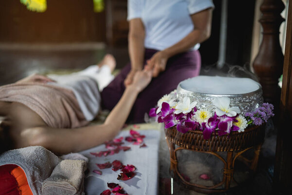 Spa massage flowers decorations while masseuse treatment of office syndrome traditional thai massage style. female masseuse doing massage treat hand, arm pain and stress for office woman tired.
