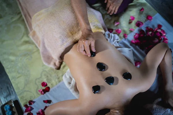 Massage and spa relaxing treatment of office syndrome using hot stone traditional thai massage style. Asian female masseuse doing massage treat back pain, arm pain, stress for woman tired from work.