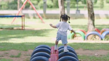 Cute asian girl smile play on school or kindergarten yard or playground. Healthy summer activity for children. Little asian girl climbing outdoors at playground. Child playing on outdoor playground.