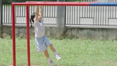 Tatlı Asyalı kız gülüşü ile okulda, anaokulunda ya da çocuk parkında bara tırman. Sağlıklı aktiviteler çocuklar. Küçük kız çocuk parkında dışarı tırmanıyor. Çocuk dışarıda oyun oynuyor..