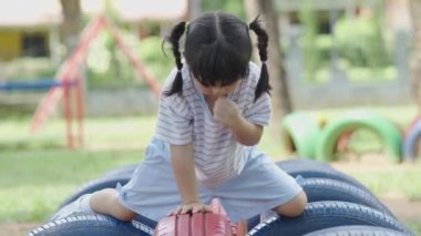 Cute asian girl smile play on school or kindergarten yard or playground. Healthy summer activity for children. Little asian girl climbing outdoors at playground. Child playing on outdoor playground.