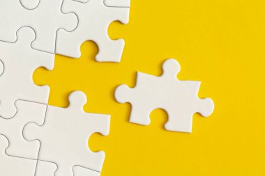 Sarı arka planda bulmacanın beyaz detayları. İş stratejisi, takım çalışması.