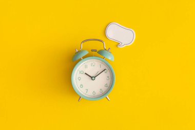 Alarm saati ve kağıt konuşma baloncuğu sarı arkaplanda metin için boşluk