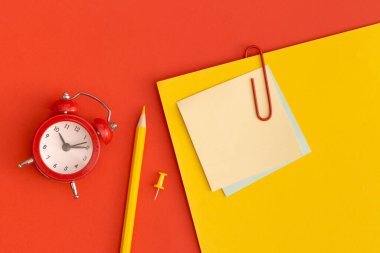 Kırmızı zemin üzerinde yazı için yeri olan kırmızı alarm saati ve yapışkan notlar