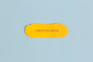 Mavi zemin üzerinde metin yaratıcı fikirleri olan sarı yırtık kağıt