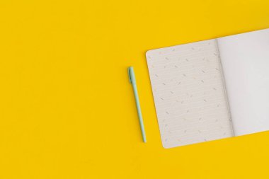 Sarı arka planda defter ve kalem. Üst Manzara. Düz yatıyordu. Okul konseptine dönelim..
