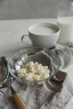 Sütlü kefir taneleri cam kasede bir bardak ve beyaz masada bir şişe kefir..