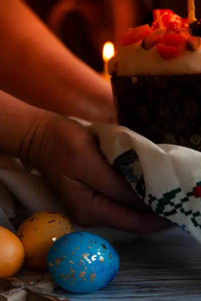 与复活节蛋糕手，东方彩绘的蛋和黑暗中的烛光，关闭 — 图库照片