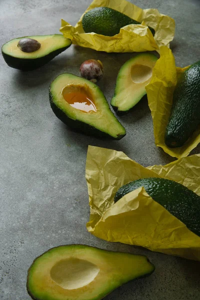 Sarı kağıda sarılı yeşil masa üzerinde avokado dilimleri. — Stok fotoğraf