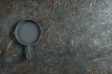 Siyah grunge arka planda yeni dökme demir tava. Kopyalama alanı olan üst görünüm