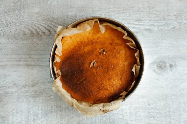 Gri ahşap bir masanın ortasında sıcak, yuvarlak, altın bir pasta. Üst görünüm