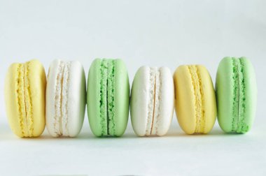 Yeşil, beyaz ve sarı badem kurabiyeleri, ya da badem kurabiyeleri, yatay bir sırada beyaz bir zemin üzerinde. Kopyalama alanı ve doğal ışıklandırma ile kenar görünüm