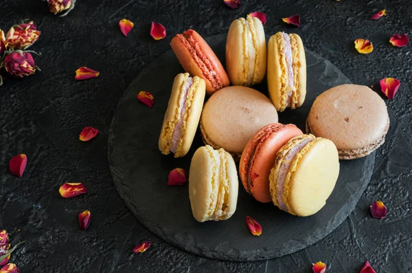 Macarons Multicolores Sur Ardoise Sur Fond Béton Noir Avec Pétales — Photo