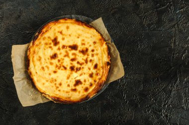 Siyah beton arka planda fotokopi alanı olan ev yapımı peynirli turta. Gün ışığı, seçici odak