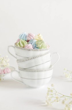 Çay fincanlarında gri arka planda renkli, havadar kremalar. Dikey resim, seçici odak