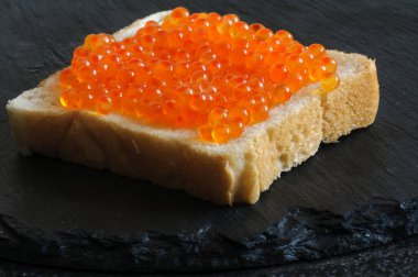 Siyah bir levhada kırmızı havyarlı kare bir sandviçe yakın çekim. Yüksek bir açıdan bak. seçici odak